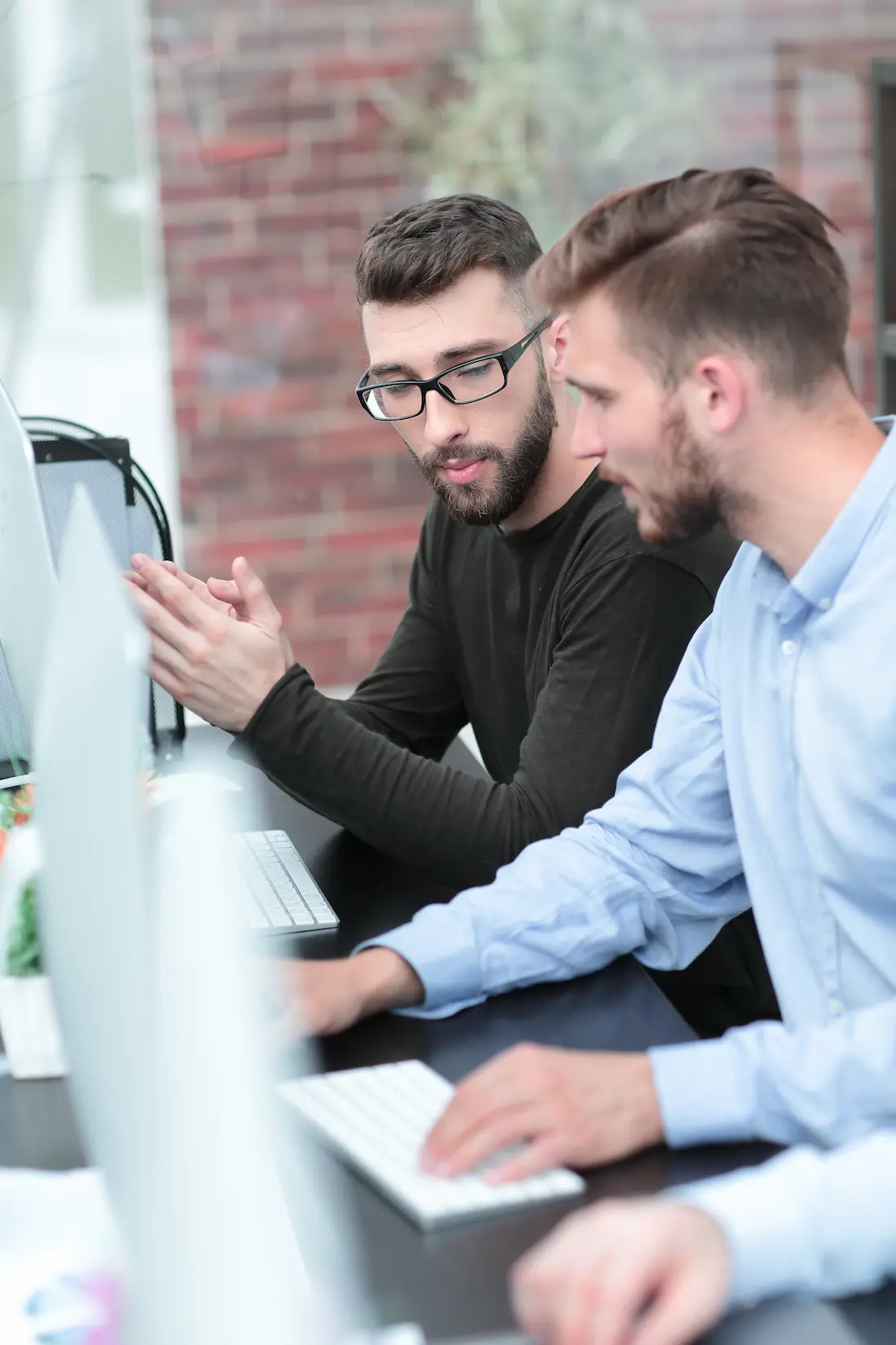 Due membri del team di MetricMate mentre collaborano e lavorano insieme a un progetto software in uno spazio di coworking luminoso.