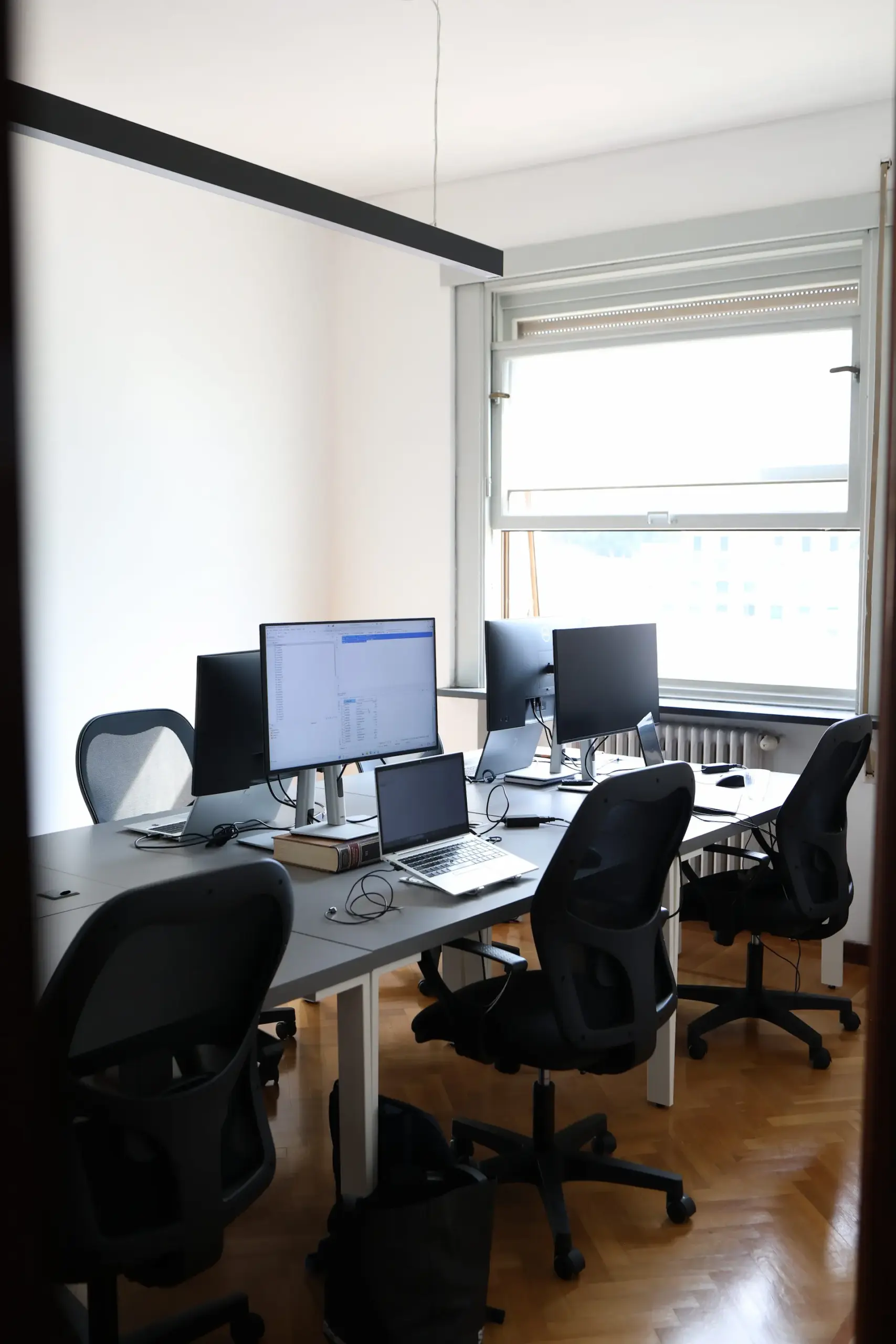 Ufficio tecnico di MetricMate con scrivanie condivise, monitor per la programmazione software e sedie ergonomiche da ufficio.