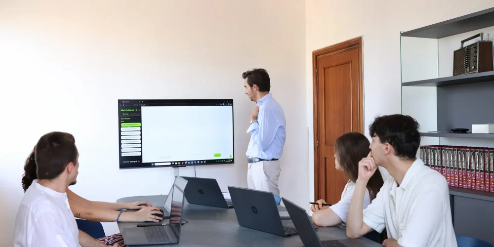 Un team di manager in sala riunioni assiste alla presentazione dei dati aziendali proiettati su uno schermo tramite la piattaforma MetricMate.