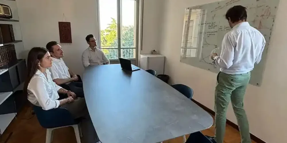 Il team di MetricMate riunito intorno al tavolo in sala riunioni durante una sessione di pianificazione strategica aziendale.